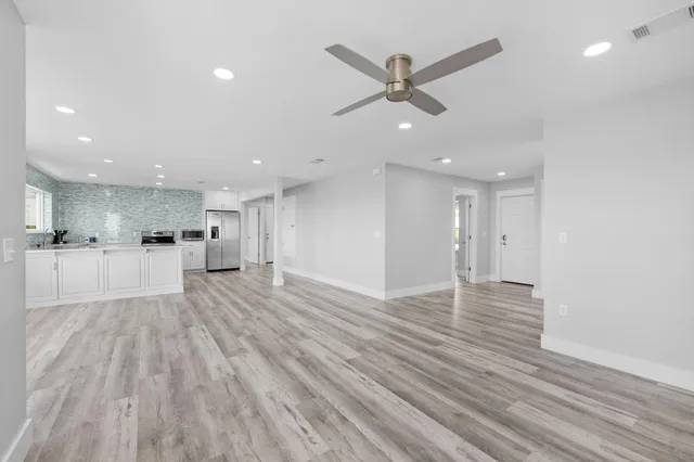 a large white kitchen with wooden floors and view living room