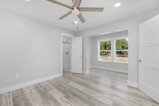 an empty room with wooden floor and windows
