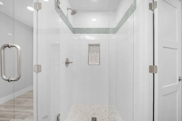 a view of a hallway with wooden floor and a bathroom