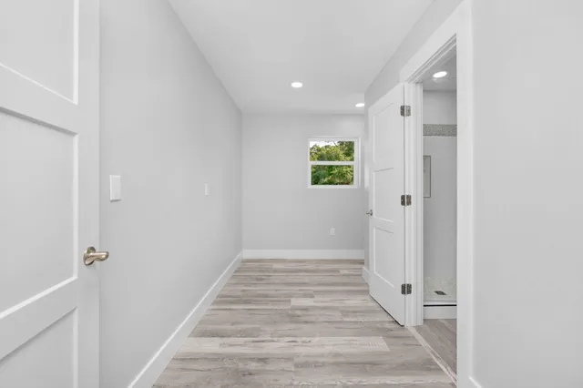 a view of a hallway with wooden floor and a bathroom
