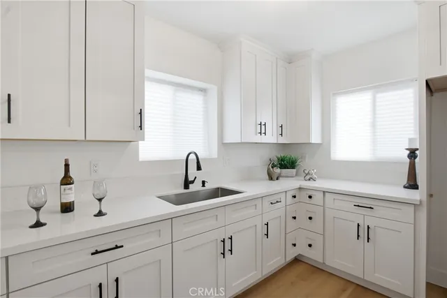 a kitchen with white cabinets and sink
