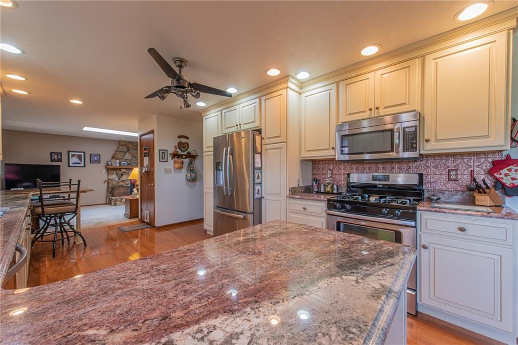 1453 Airport Road Vandergrift, PA 15690 - Photo 10 of 48 a kitchen with stainless steel appliances kitchen island granite countertop a refrigerator a stove a sink a dining table and chairs with wooden floor