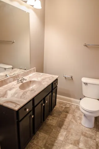a bathroom with a granite countertop sink a toilet and a mirror