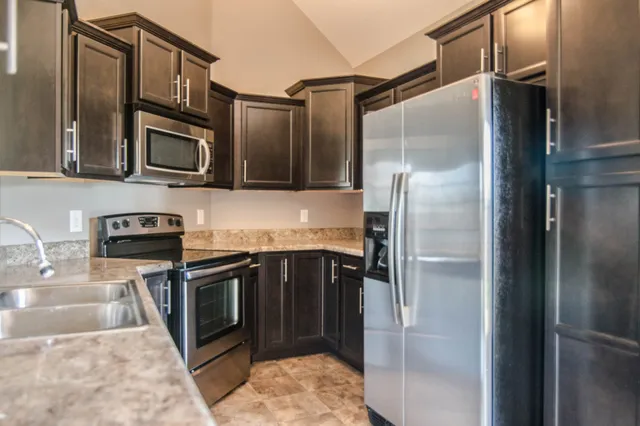 a kitchen with stainless steel appliances granite countertop a refrigerator and a sink