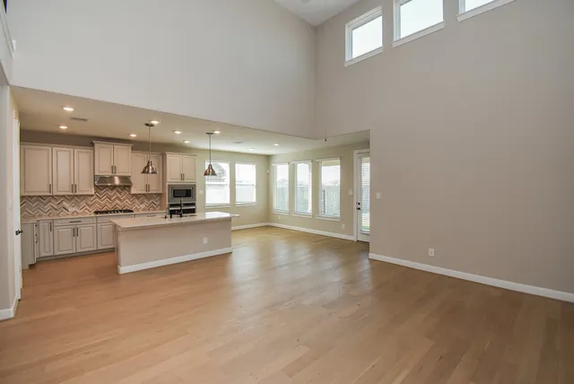 a large kitchen with kitchen island a large counter top a sink stainless steel appliances and cabinets