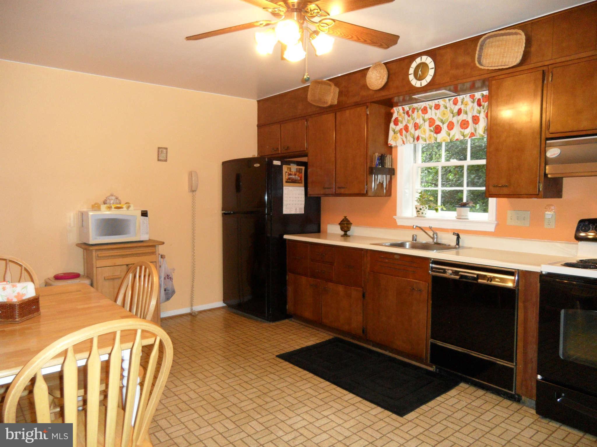 5908 Walhonding Road Bethesda, MD 20816 - Photo 8 of 26 a kitchen with stainless steel appliances kitchen island granite countertop a refrigerator a sink dishwasher a dining table and chairs with wooden floor