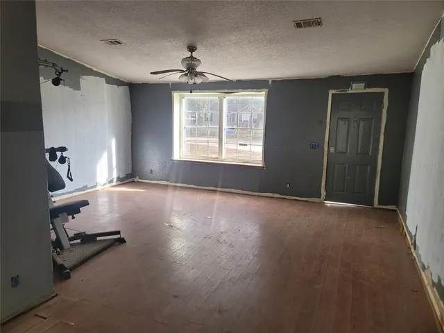 a view of empty room with windows and ceiling fan