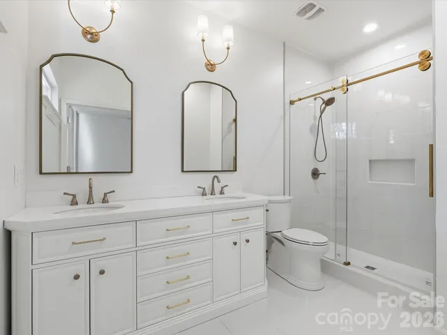 a bathroom with double vanity a toilet a mirror and vanity