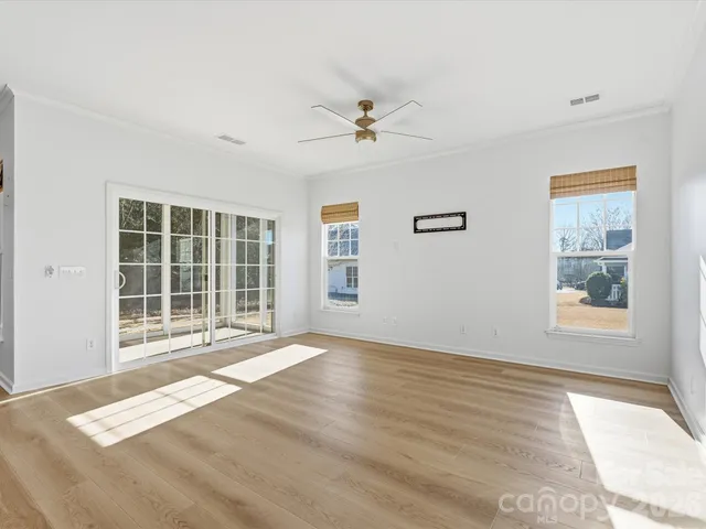 a view of an empty room with window and wooden floor