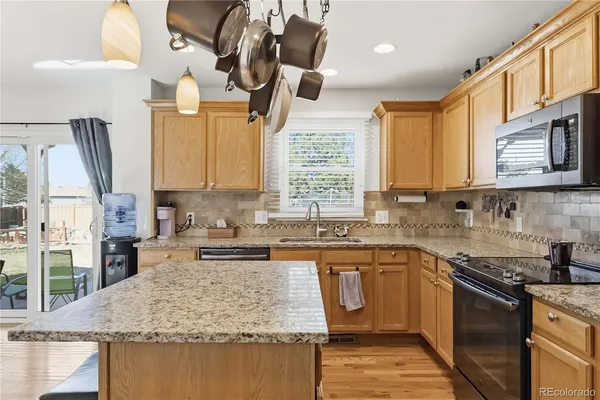 a kitchen with stainless steel appliances granite countertop a sink a stove and a wooden cabinets