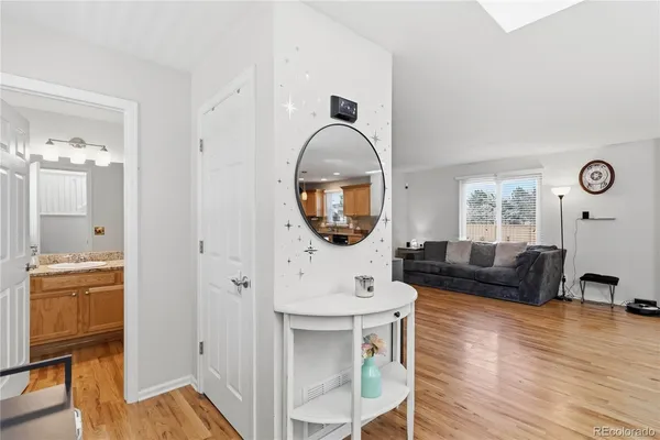 a living room with furniture a mirror and a wooden floor
