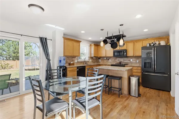 a kitchen with granite countertop a table chairs microwave and cabinets