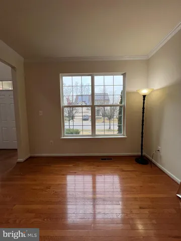 a view of an empty room with wooden floor and a ceiling fan