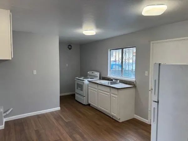 a kitchen with sink a stove and wooden floor
