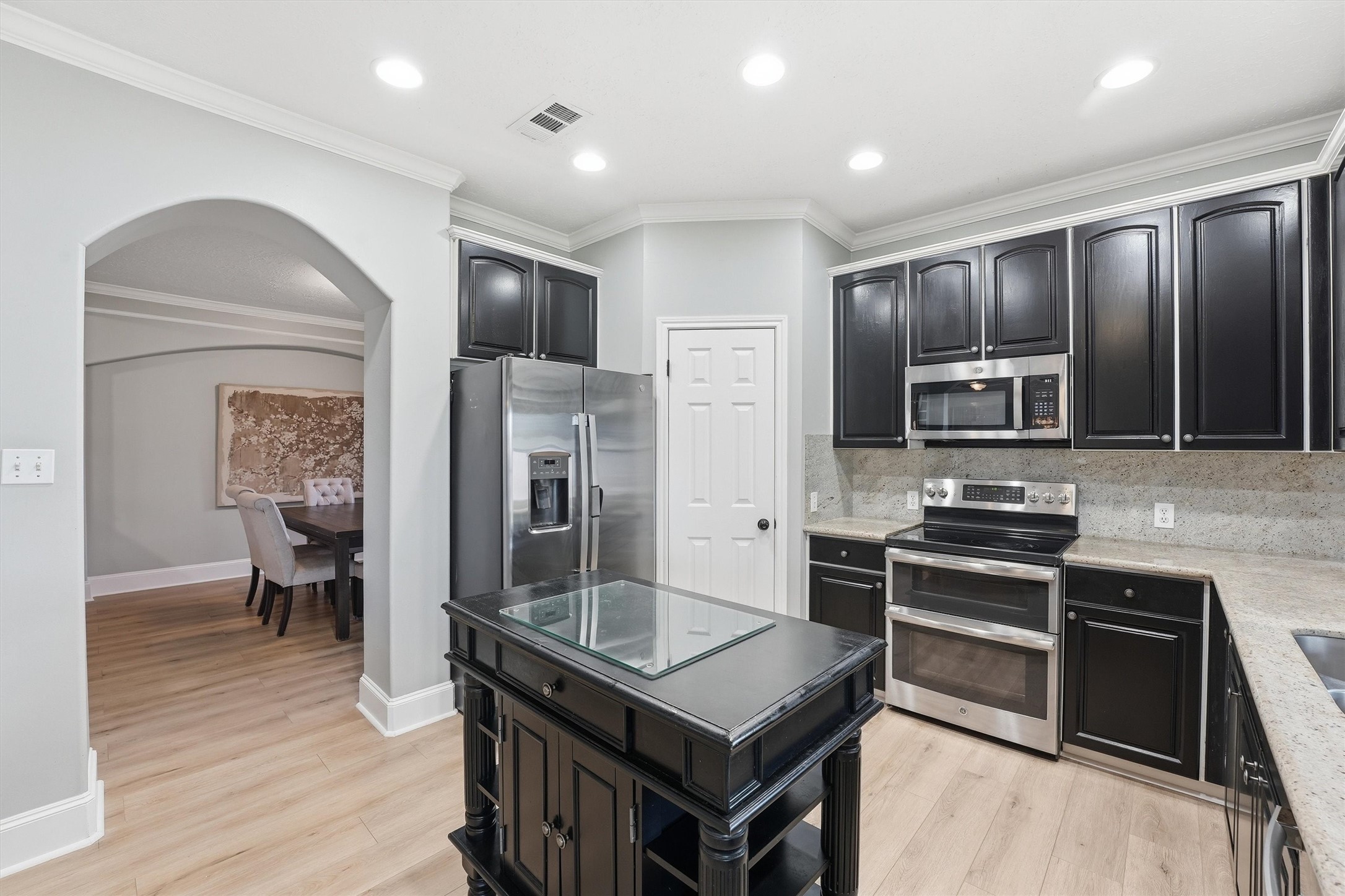 8827 Mile Run Road Humble, TX 77346 - Photo 14 of 37 a kitchen with stainless steel appliances granite countertop a stove top oven a sink dishwasher a refrigerator and cabinets with wooden floor