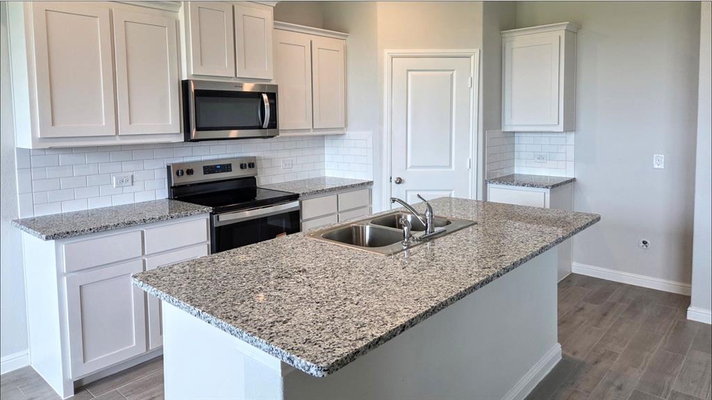a kitchen with kitchen island granite countertop a sink a counter top space appliances and cabinets