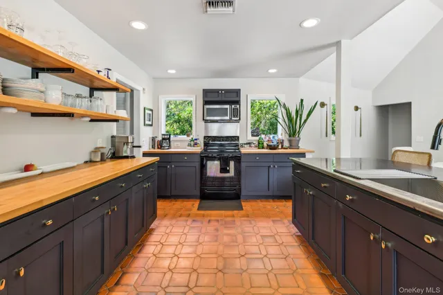 a very nice looking kitchen with granite countertop a large window and white cabinets