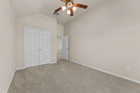 an empty room with chandelier fan and windows