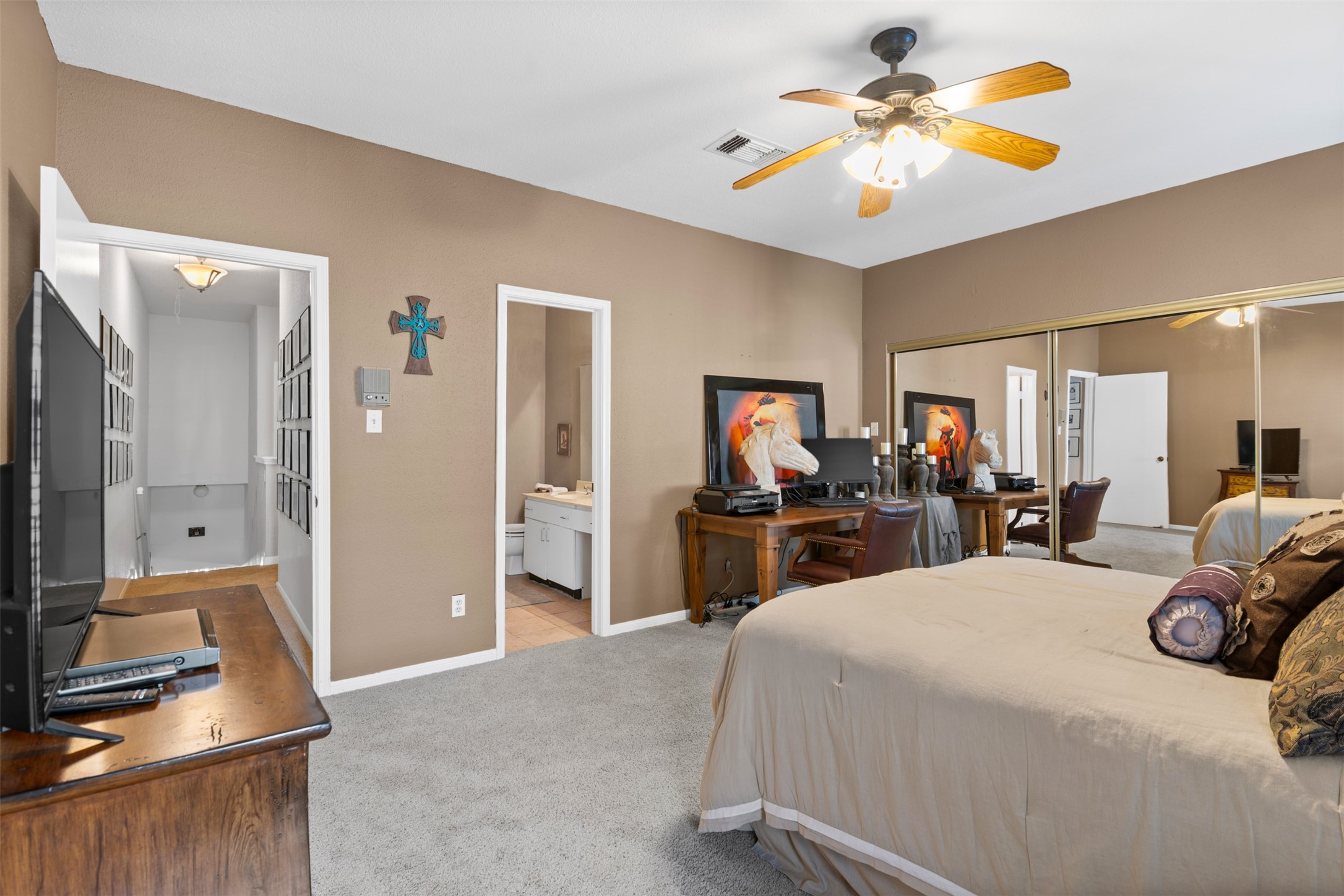 6000 Reims Road, Unit 2307 Houston, TX 77036 - Photo 17 of 26 This spacious guest bedroom features neutral walls, carpeted flooring, a ceiling fan, and ample natural light. It includes a large mirrored closet, a desk area, and an en-suite bathroom.
