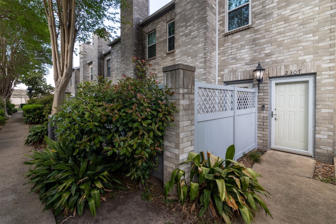 6000 Reims Road, Unit 2307 Houston, TX 77036 - Photo 2 of 26 Features a front patio area surrounded by lush greenery.