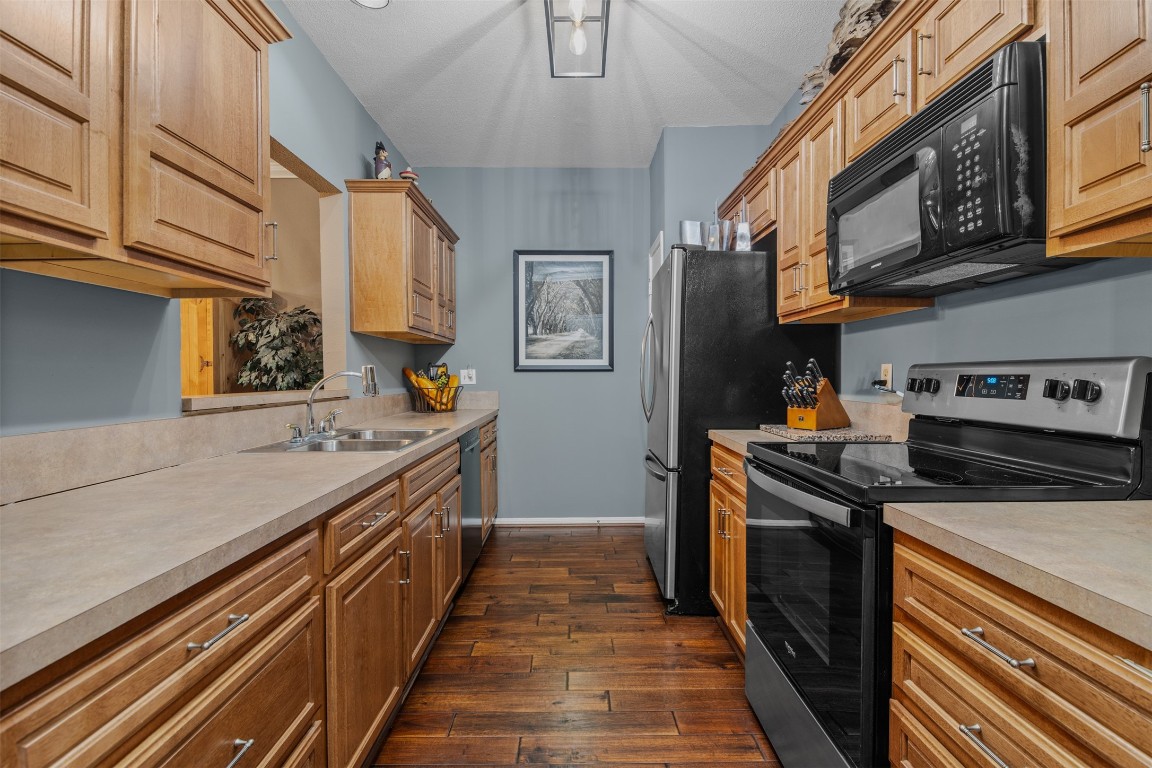 6000 Reims Road, Unit 2307 Houston, TX 77036 - Photo 6 of 26 This tastefully updated kitchen features sleek stainless steel appliances, ample wooden cabinetry, with its wood flooring and neutral countertops. The space is well-lit and efficiently organized for functionality.