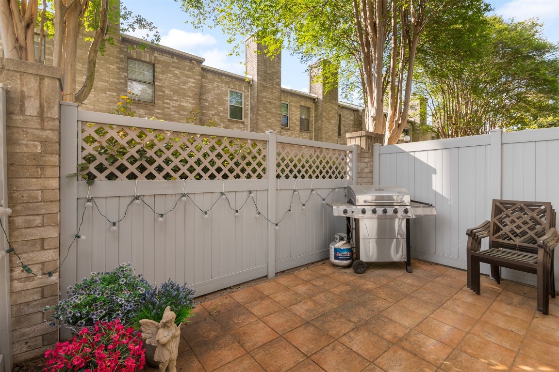 6000 Reims Road, Unit 2307 Houston, TX 77036 - Photo 9 of 26 This cozy patio features a tiled floor, privacy fencing, a gas grill, and seating, making it perfect for outdoor relaxation and entertaining. Lush plants and string lights add charm to the space.