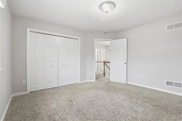 an empty room with a ceiling fan and carpet