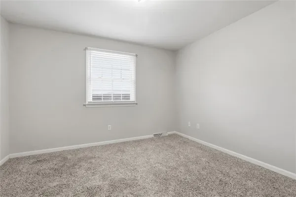 an empty room with a ceiling fan and carpet