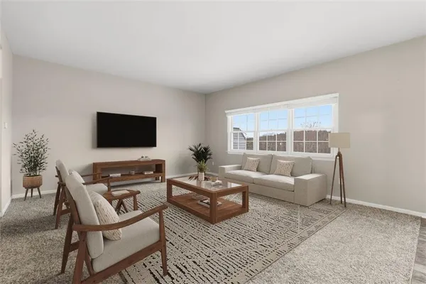 a living room with furniture a flat screen tv and a window