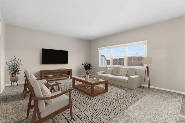 a living room with furniture a flat screen tv and a window