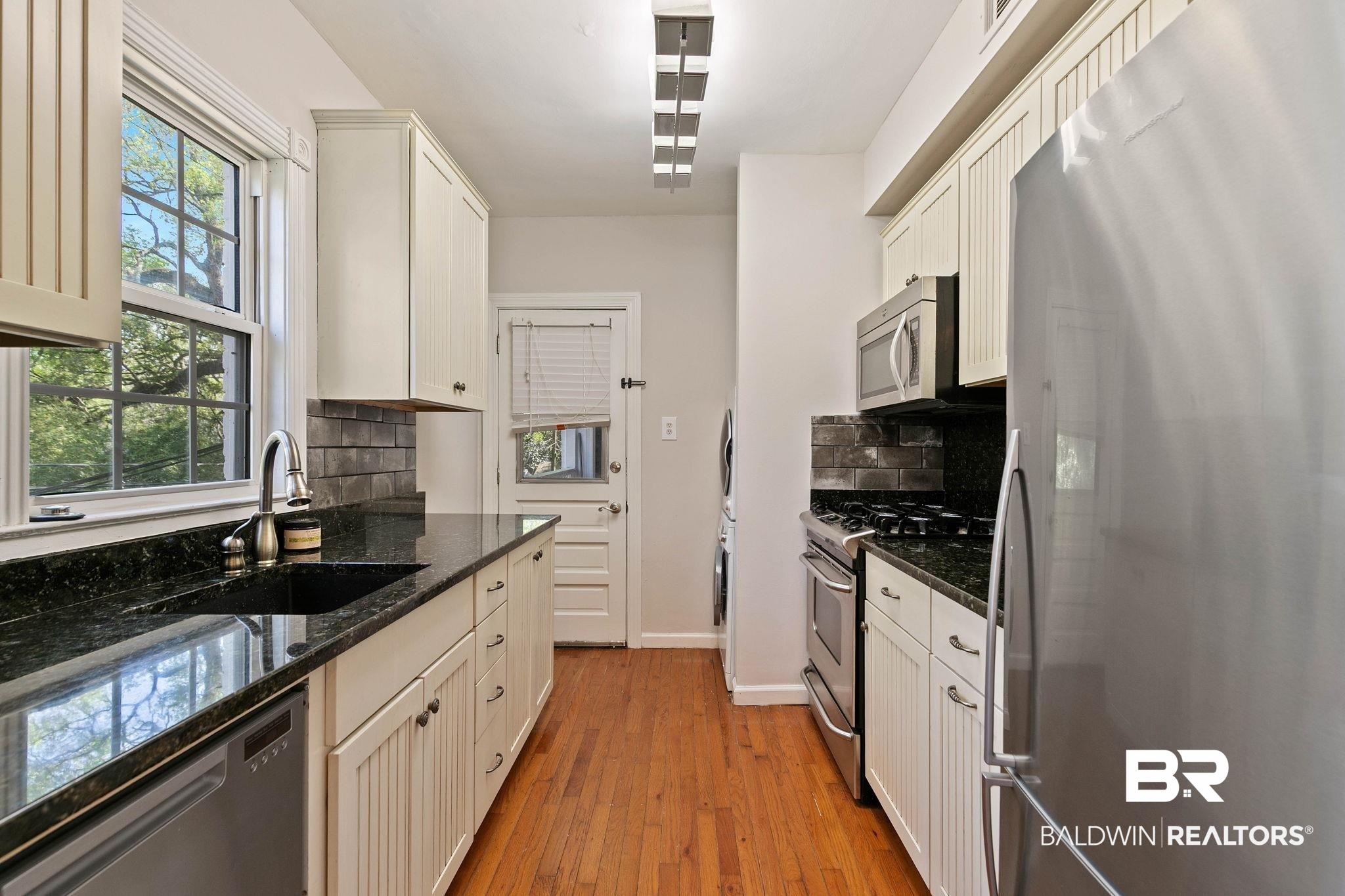 214 Upham Street, Unit 8D Mobile, AL 36607 - Photo 9 of 36 Kitchen featuring stainless steel appliances, dark stone counters, light wood-type flooring, decorative backsplash, and white cabinets