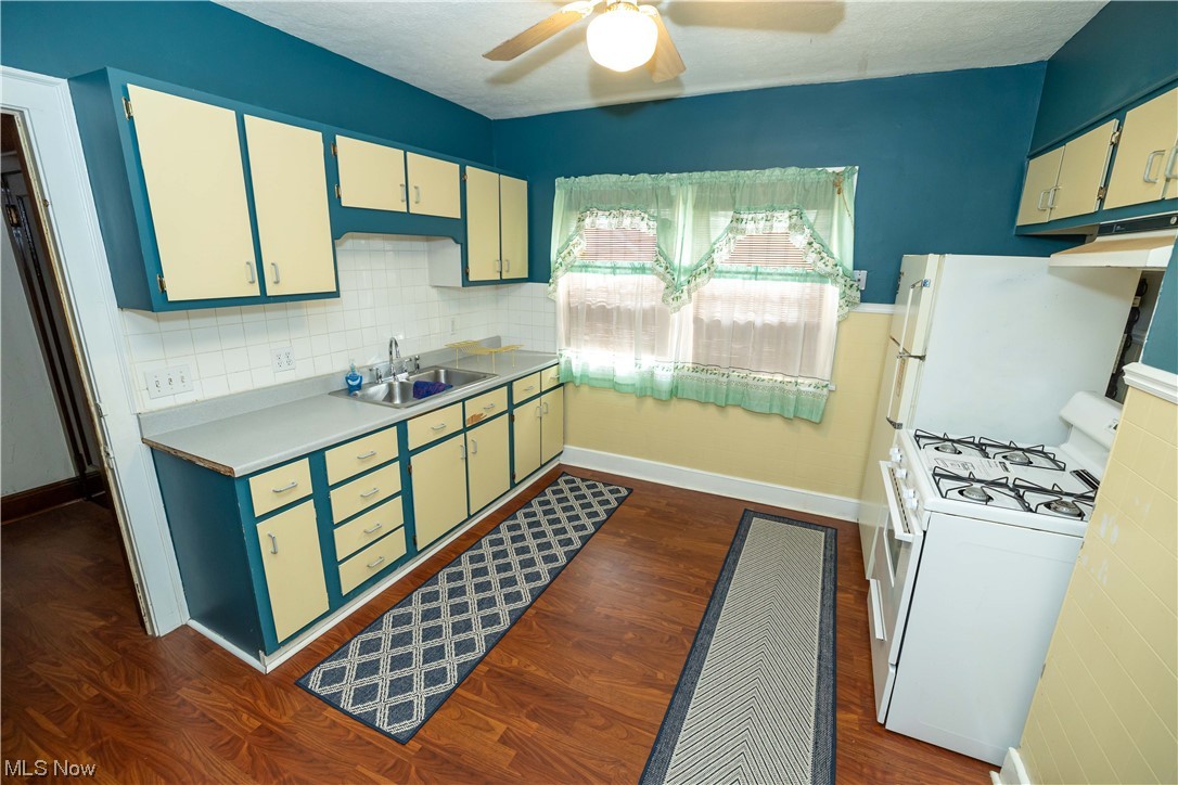 10105 Unity Avenue Cleveland, OH 44111 - Photo 14 of 35 Kitchen featuring tasteful backsplash, ceiling fan, dark hardwood floors, white range with gas cooktop, and sink