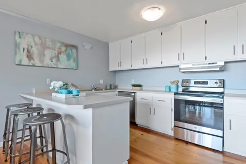 a kitchen with stainless steel appliances granite countertop white cabinets a stove top oven with wooden floor