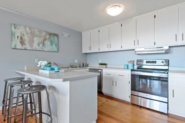 a kitchen with stainless steel appliances granite countertop white cabinets a stove top oven with wooden floor