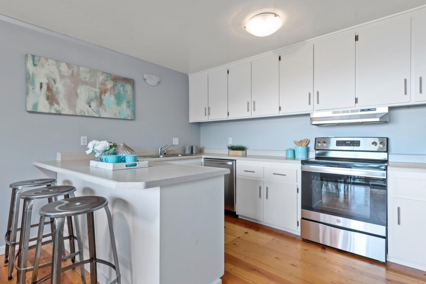 14826 Skyline Boulevard, Unit 3 Woodside, CA 94062 - Photo 6 of 13 a kitchen with stainless steel appliances granite countertop white cabinets a stove top oven with wooden floor