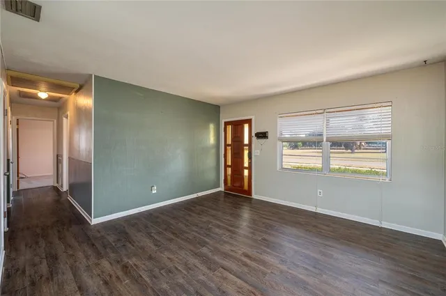 an empty room with wooden floor and windows
