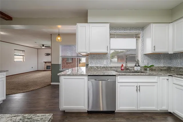 a kitchen with stainless steel appliances granite countertop a stove a sink and white cabinets