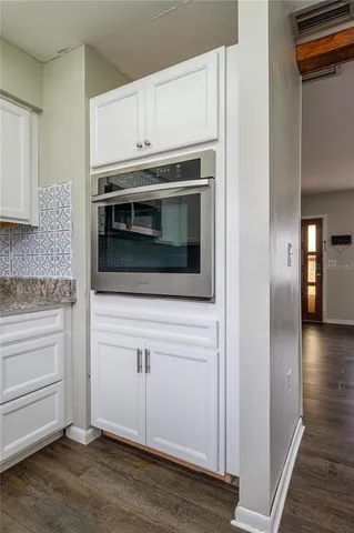 a kitchen with stainless steel appliances white cabinets and a wooden floor