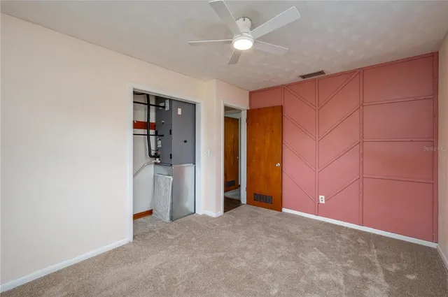 an empty room with closet and a ceiling fan