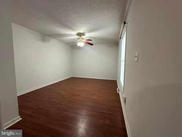 an empty room with wooden floor fan and window