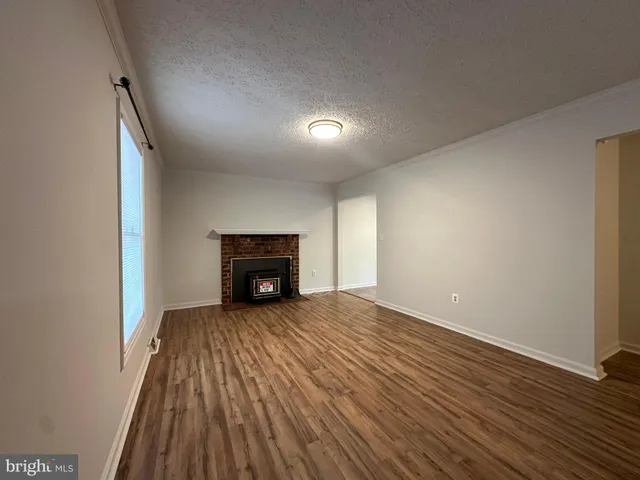 an empty room with wooden floor fireplace and windows