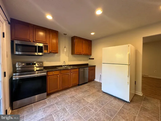 a kitchen with stainless steel appliances granite countertop a refrigerator a stove a sink and a microwave