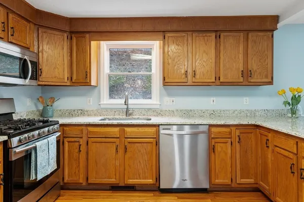 a kitchen with stainless steel appliances granite countertop wooden cabinets a sink and a dishwasher