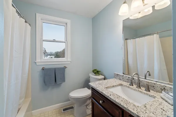 a bathroom with a granite countertop sink a toilet and a mirror