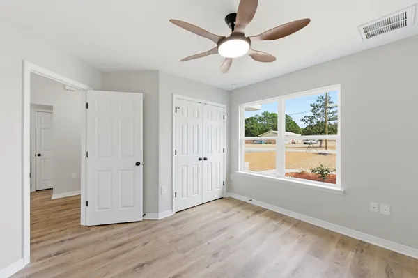 a view of an empty room with a window and wooden floor