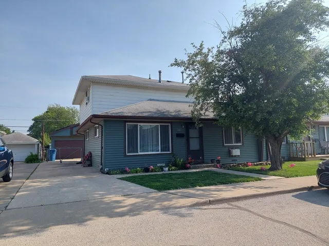a view of a house with a yard plants and large tree