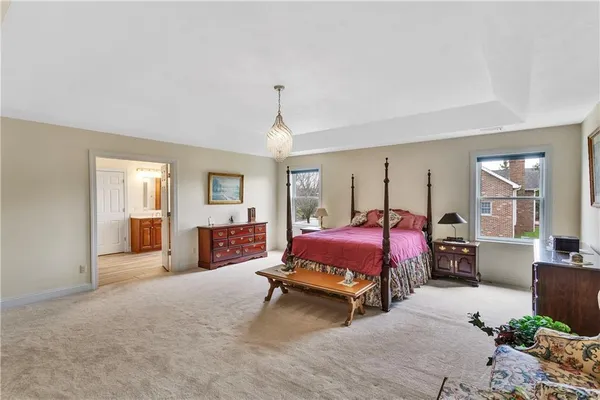 a spacious bedroom with a bed large window and chandelier