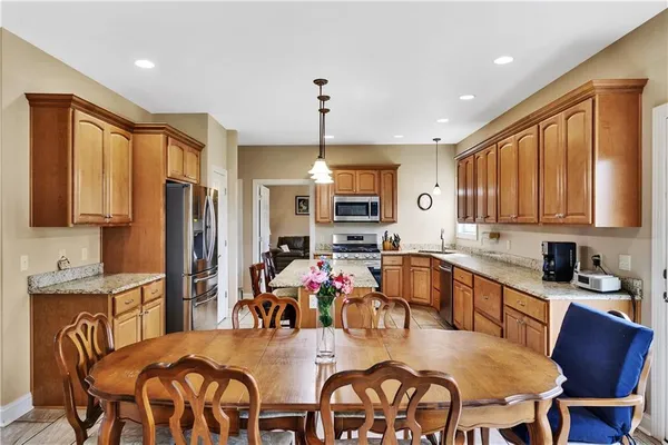 a kitchen with stainless steel appliances granite countertop a stove a sink dishwasher a dining table and chairs with wooden floor