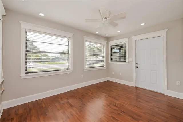 a view of an empty room with wooden floor and a window