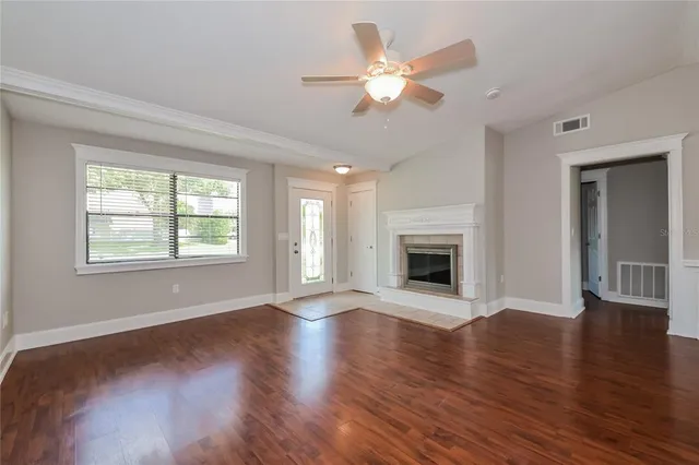 a view of an empty room with wooden floor and a window
